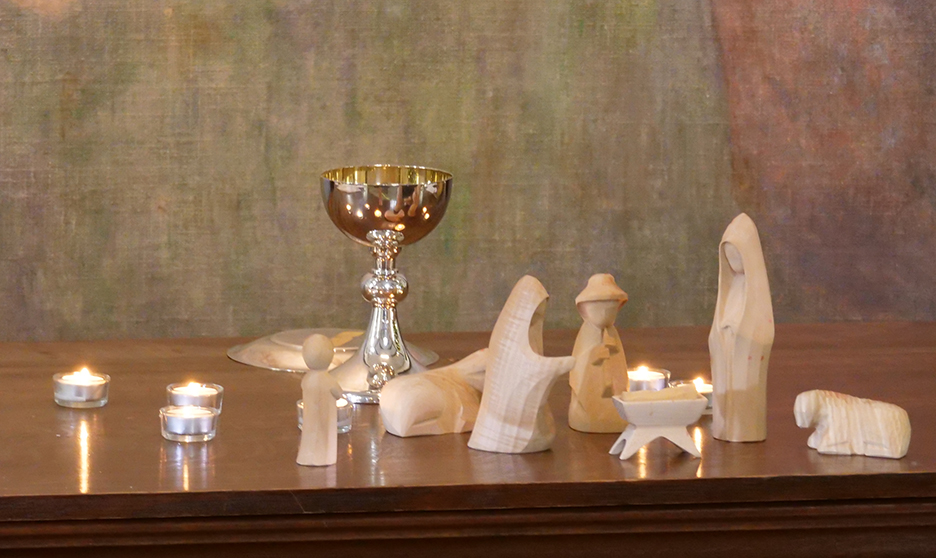 wooden nativity scene on alter with tea light candles and silver goblet behind represents learning together