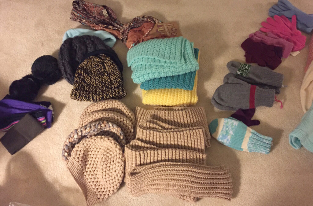 a photo displaying knitted and crocheted hats, mittens and gloves on a blanket.