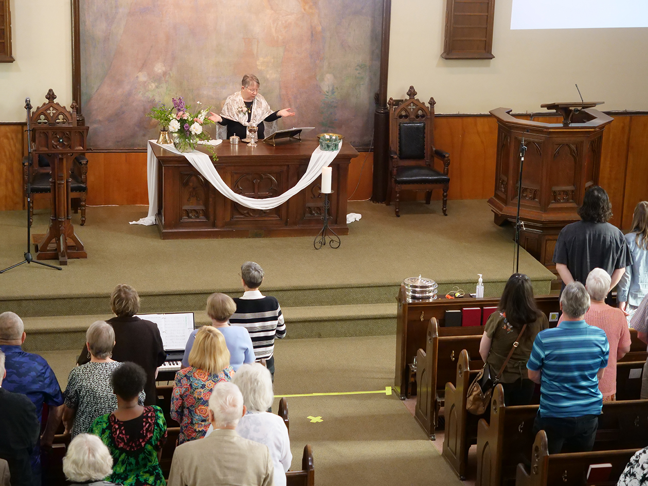 Pastor Loretta at the alter with her hands outstretched as she performs a sermon to the congregation