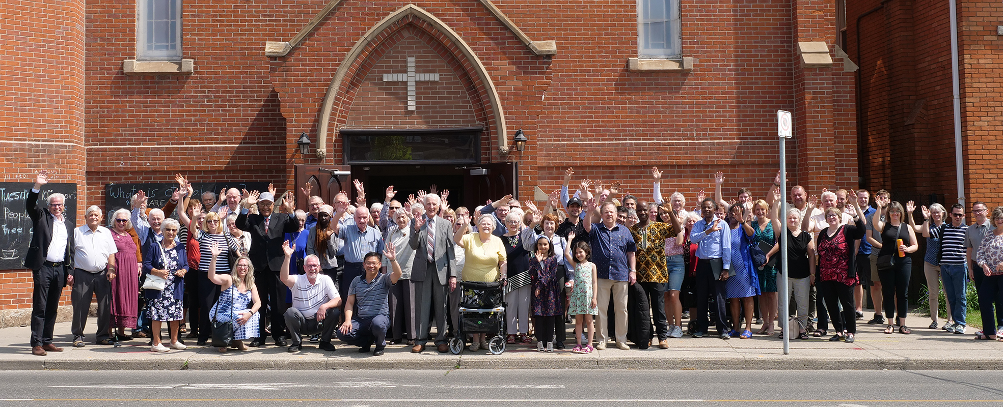 Trinity Lutheran Church congregation members standing outside of the church and all waving